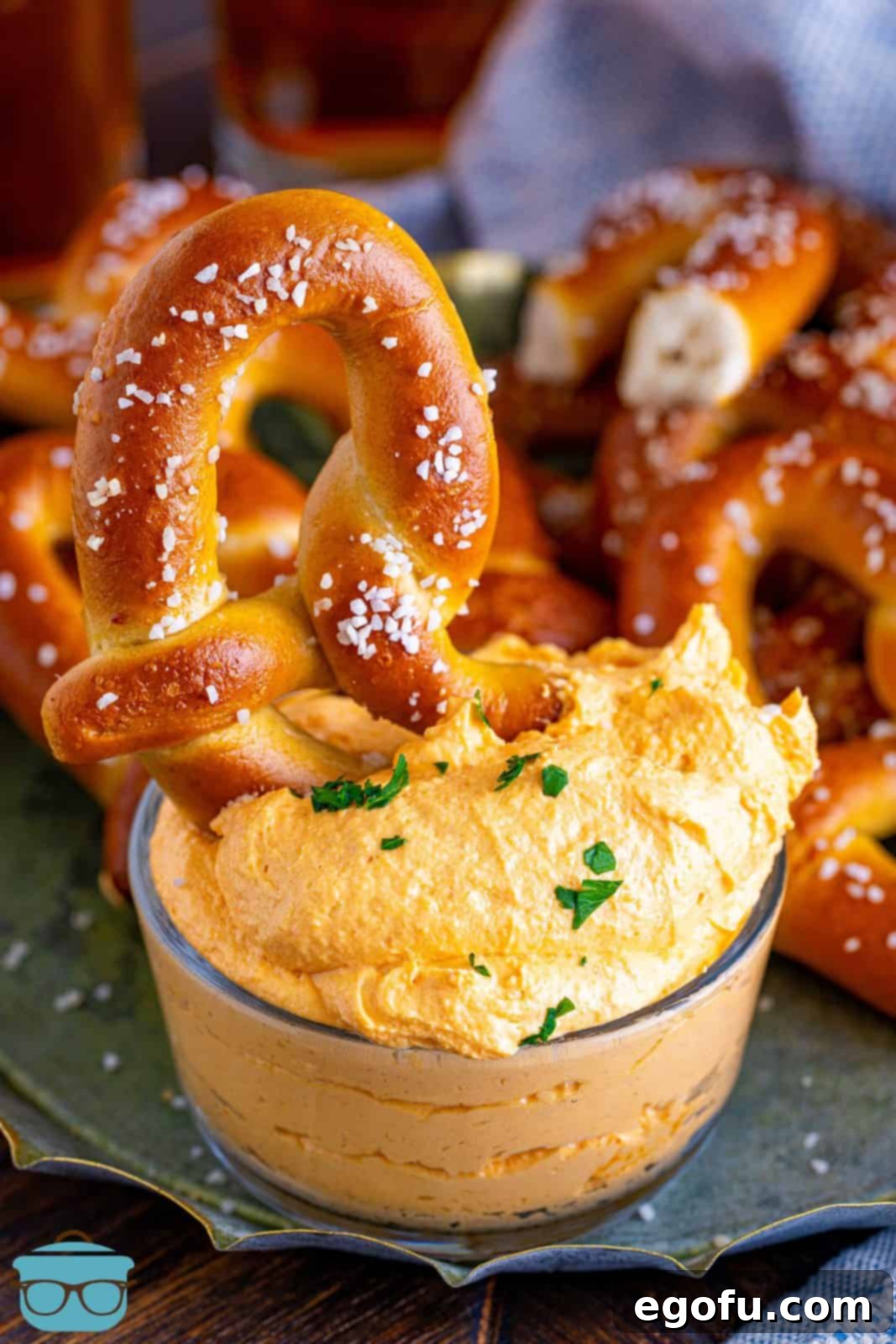 One pretzel sticking out of bowl of Beer Cheese Dip, inviting guests to enjoy.