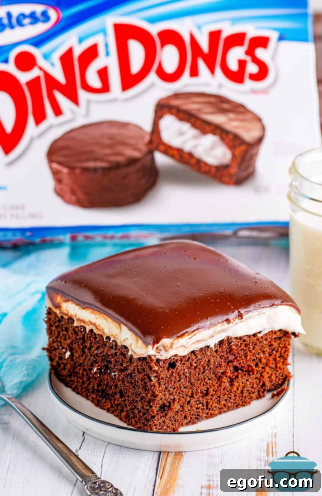 Slice of Ding Dong Cake on white plate in front of a box of Ding Dongs.