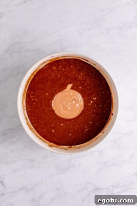 Chocolate sour cream mixture added to cake mixture in bowl.