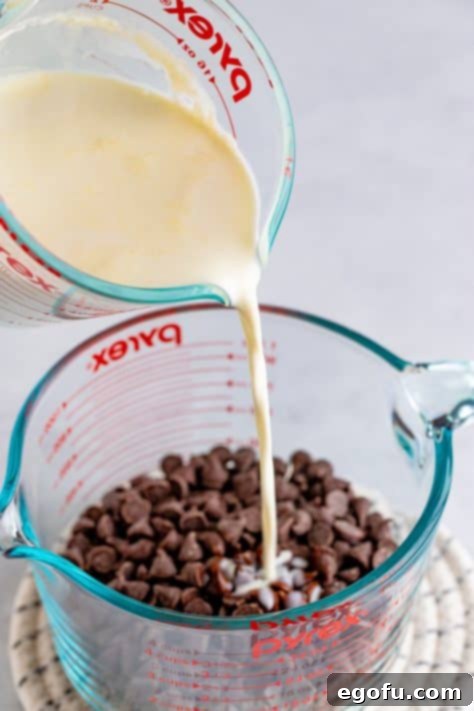 Ganache being made with heavy cream being poured over chocolate chips.