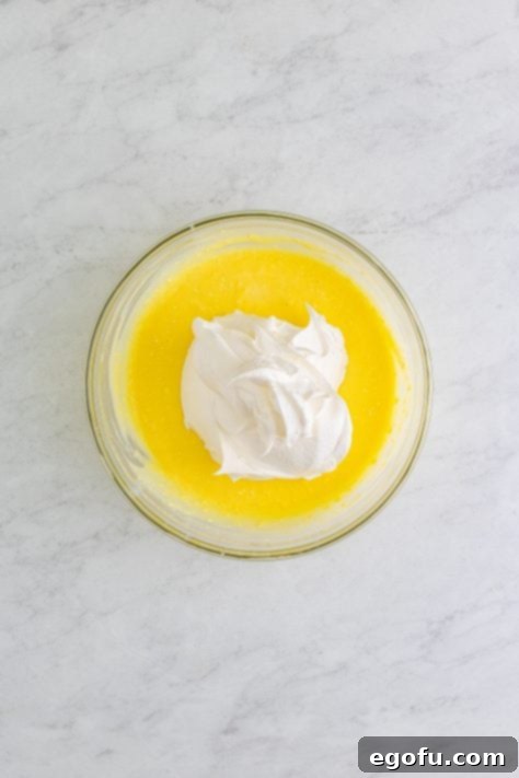 whipped topping added to pudding and milk mixture in bowl.