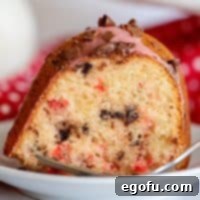 Square image of Cherry Chocolate Chip Cake close up on white plate.