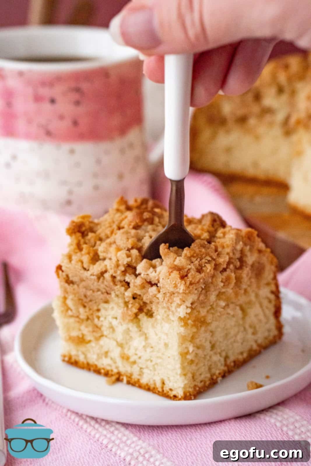 A fork piercing into a slice of Bisquick Coffee Cake, revealing its moist interior and generous streusel layer.