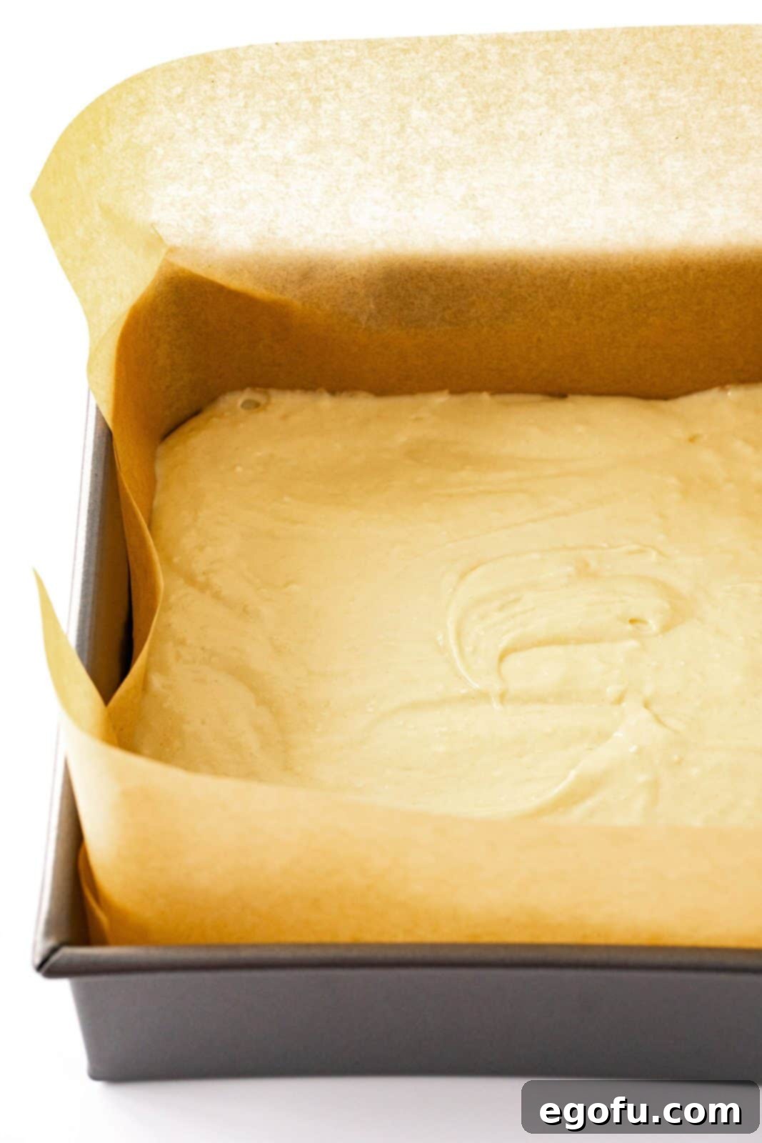 The rich coffee cake batter smoothly spread into a parchment-lined baking pan, forming a perfect base for the topping.