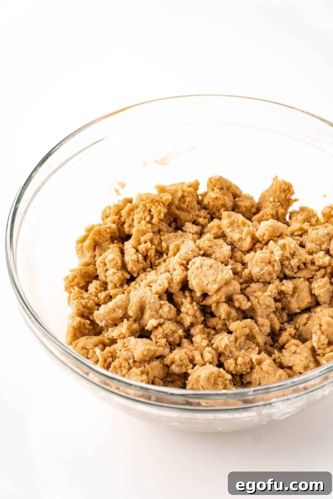 The streusel topping ingredients, including melted butter, Bisquick, brown sugar, and cinnamon, perfectly mixed into large, inviting crumb clusters in a bowl.