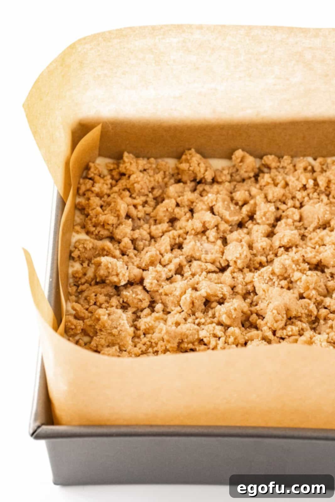 The coffee cake batter completely covered with a thick, abundant layer of cinnamon streusel topping, ready for baking.
