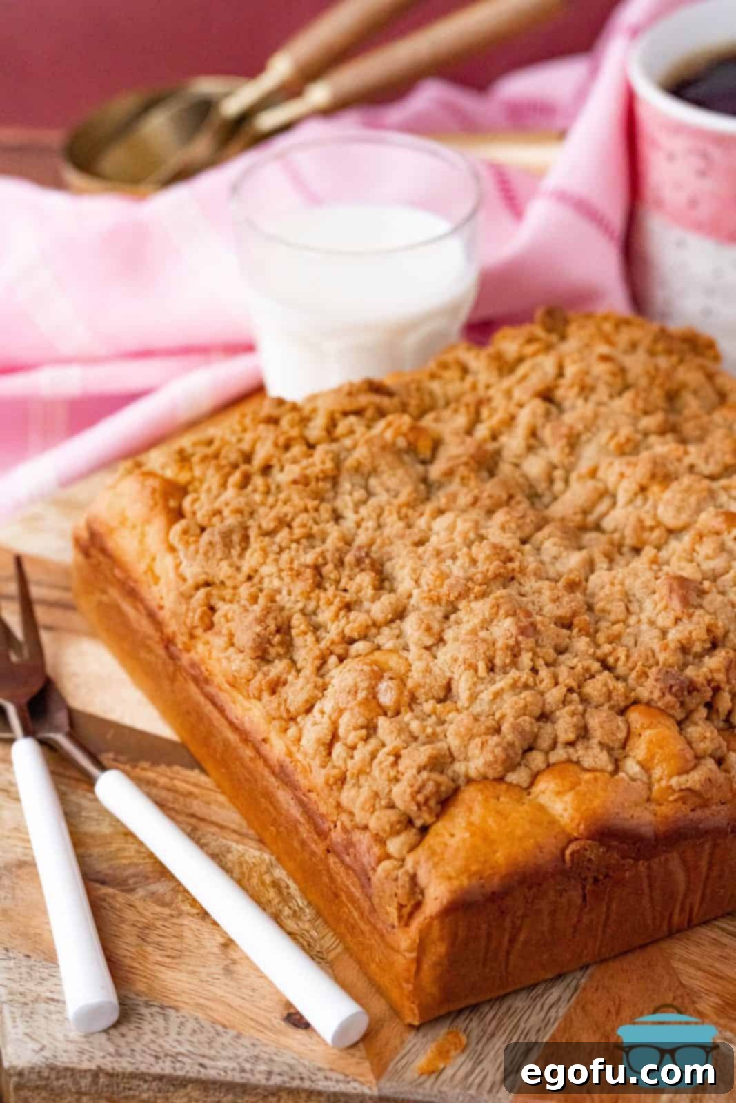 A freshly baked, uncut Bisquick Coffee Cake cooling on a cutting board, its thick streusel topping glistening.