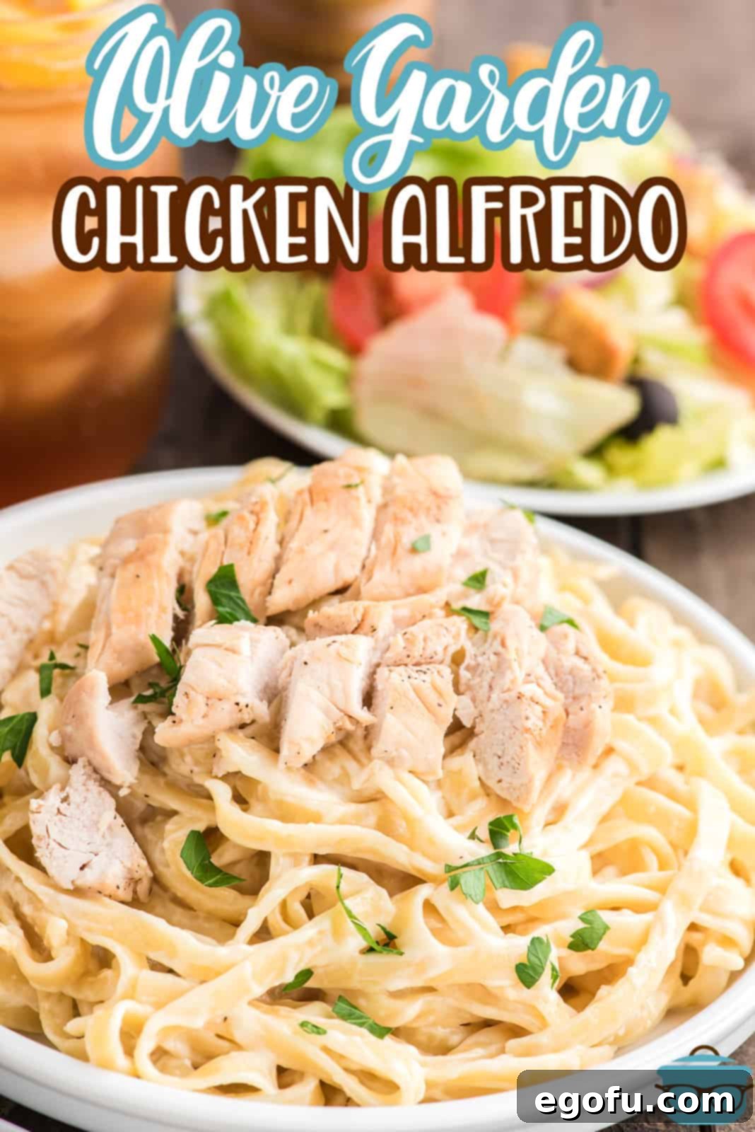 Overhead view of a perfectly plated Olive Garden Chicken Alfredo, ready to be served, accompanied by a fresh side salad and golden breadsticks.