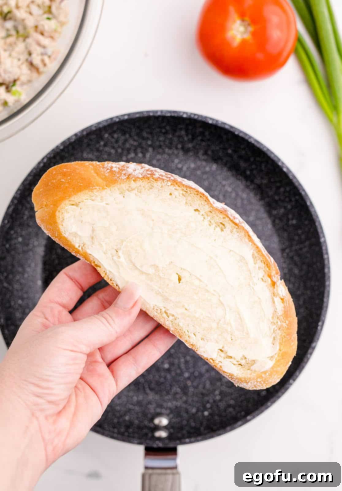 Golden Grilled Tuna Melt 6 Hand holding up a buttered slice of bread.