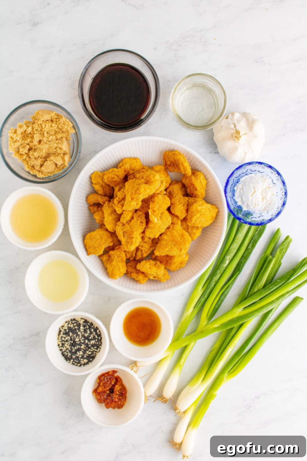 Ingredients needed: light brown sugar, rice wine vinegar, low sodium soy sauce, sesame oil, cooked popcorn chicken, water, cornstarch, vegetable oil, scallions, garlic, chili paste and sesame seeds.