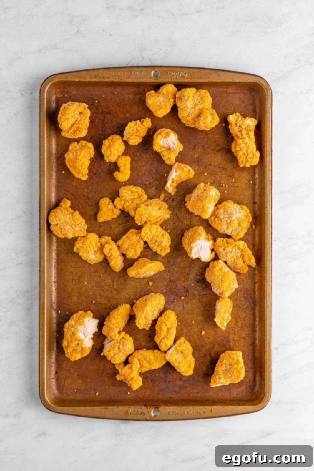 Cooked popcorn chicken on baking sheet.
