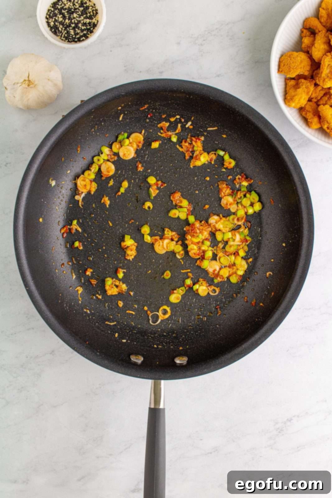 Vegetable oil, scallions, garlic, and chili paste added to skillet and sauteed.