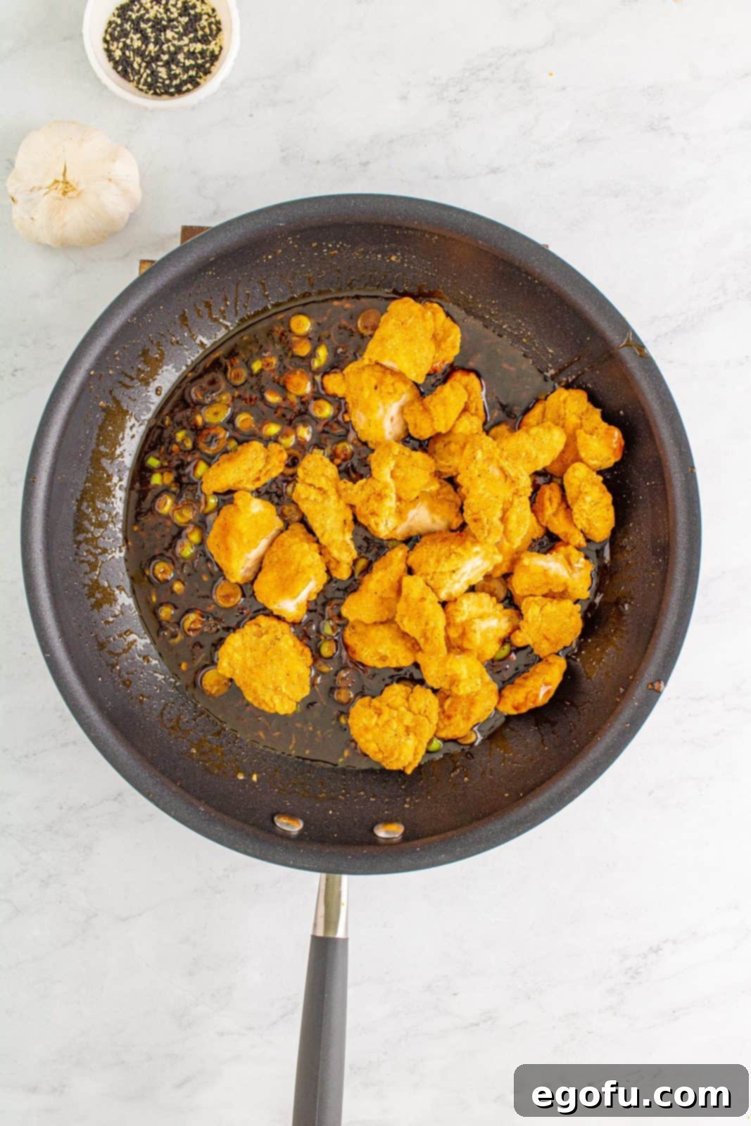 Cooked popcorn chicken added to bubbling sauce.