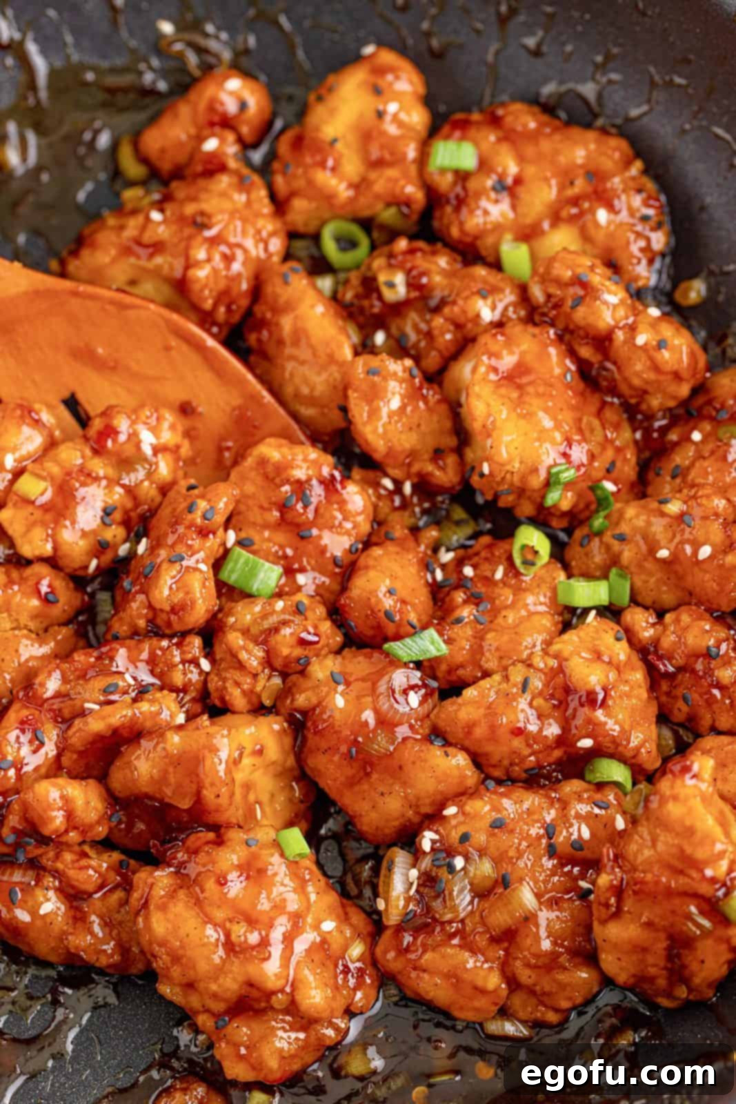 Close up of Easy Sesame Chicken in skillet with wooden spatula.