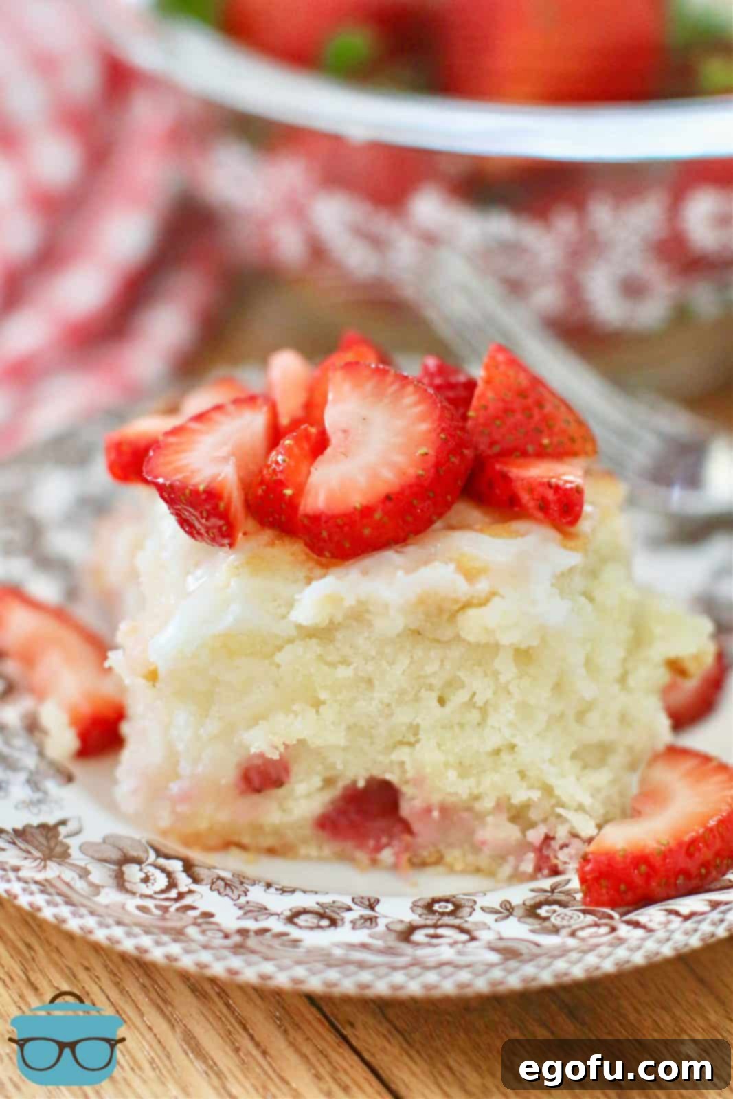 A single Strawberry Butter Dip Biscuit on a white plate, elegantly topped with sliced fresh strawberries, showcasing its golden crust and soft interior.