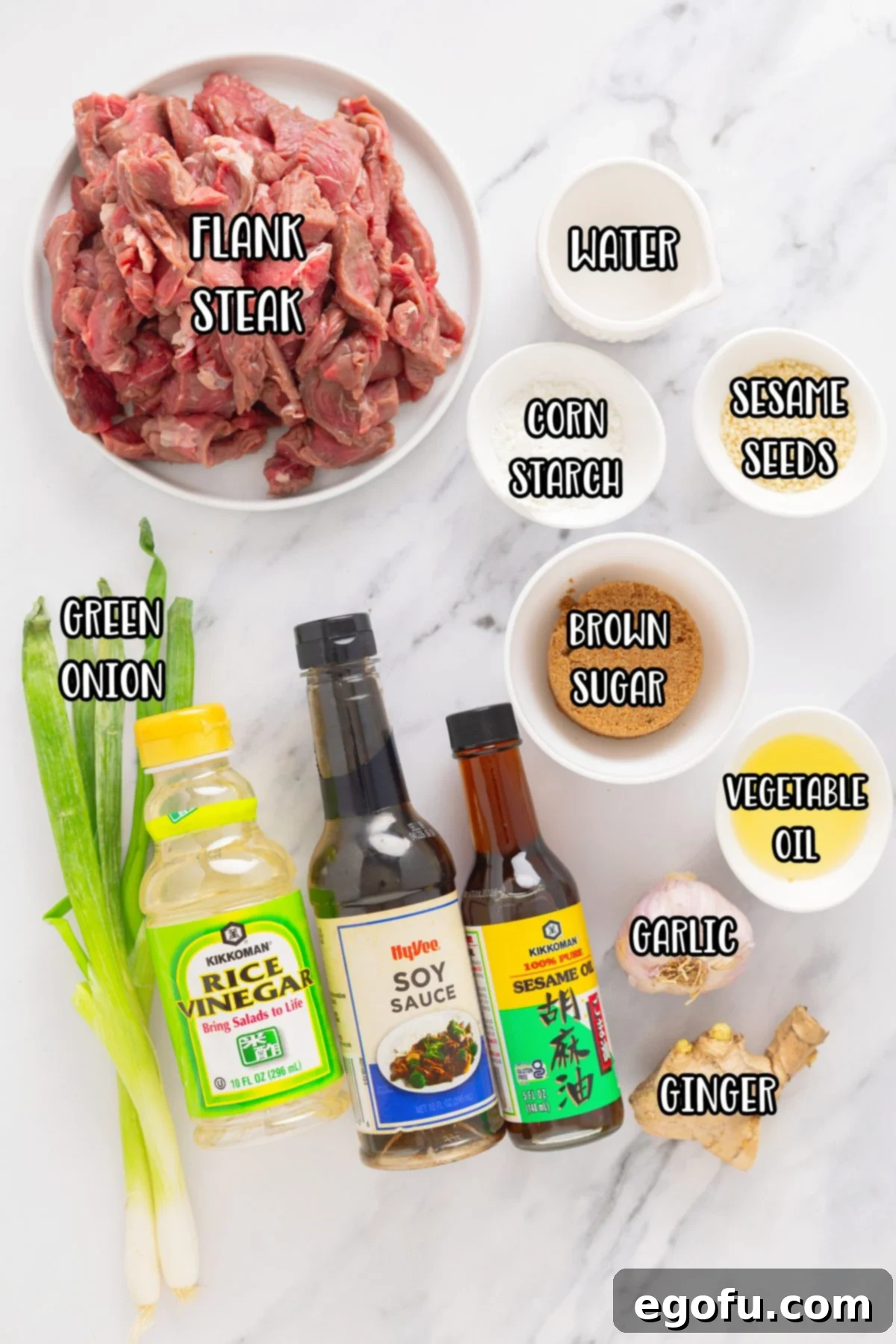A collection of ingredients for Beef Teriyaki: flank steak, cornstarch, vegetable oil, sesame oil, garlic, fresh ginger, low-sodium soy sauce, brown sugar, water, rice vinegar, sesame seeds, and sliced green onions.
