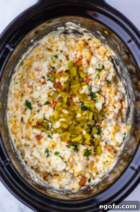 Jalalpenos and cheese being added to a Corn Dip in the Slow Cooker.