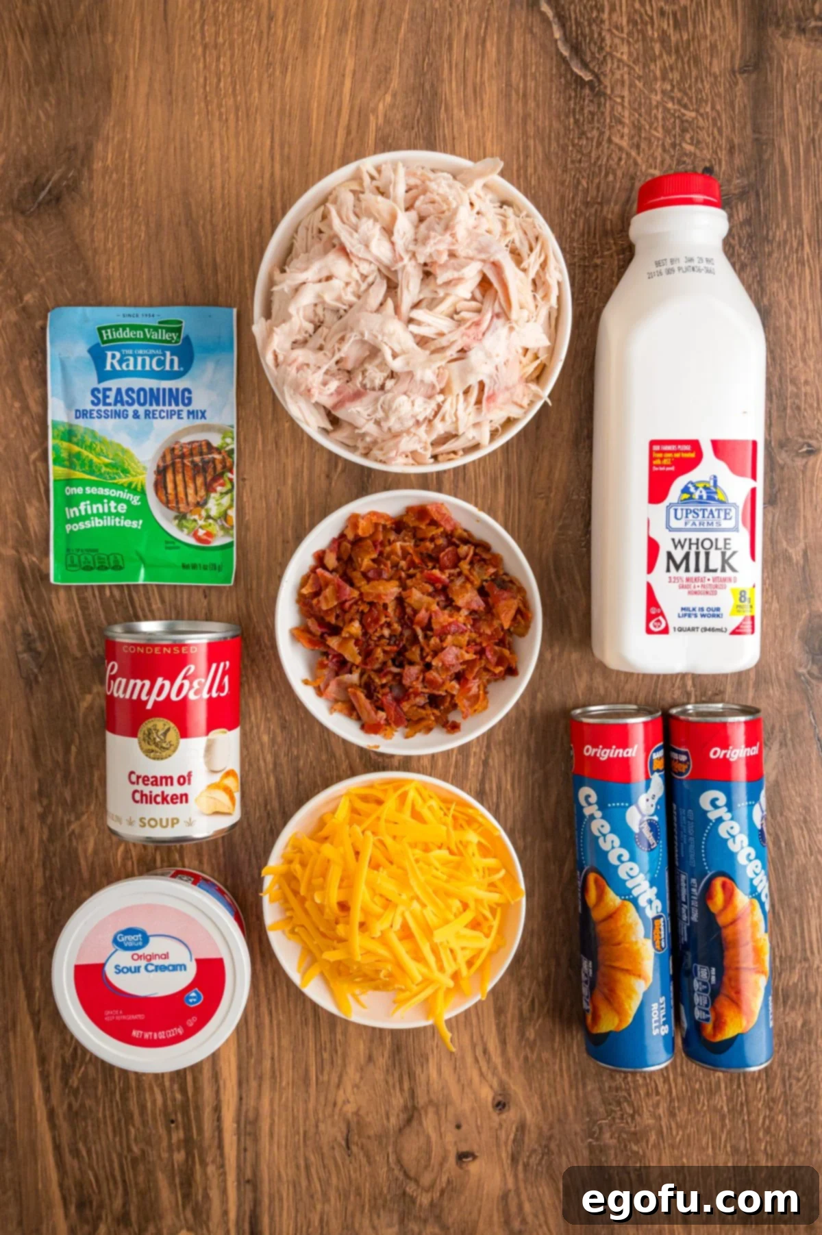 Cheesy Chicken Crescents 5 Shredded cooked chicken, sour cream, ranch seasoning mix, shredded cheddar cheese, cooked and crumbled bacon, crescent roll dough, cream of chicken soup, whole milk, and additional shredded cheddar cheese.