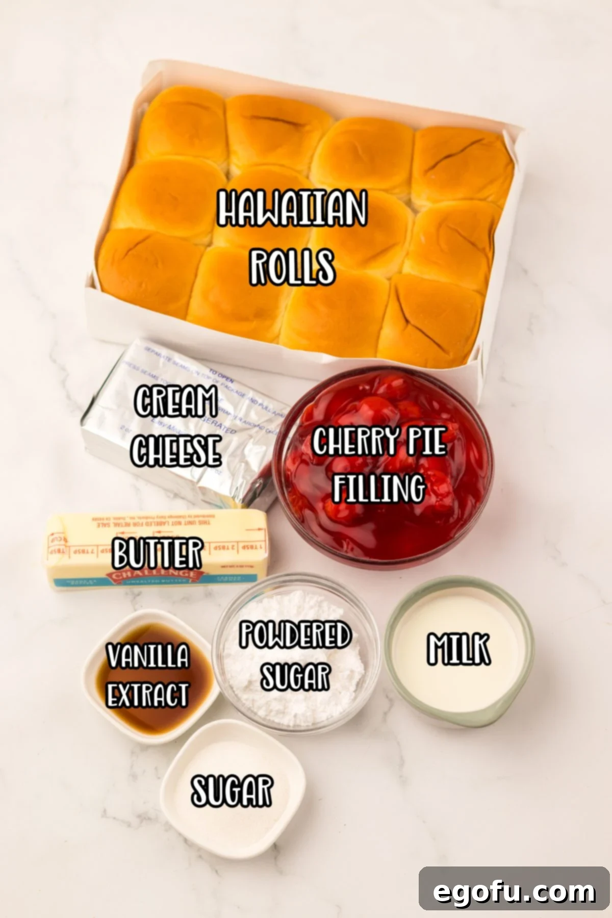 Hawaiian Sweet Roll Cherry Pastries 4 A well-lit photo showcasing the ingredients needed to make Hawaiian Roll Cherry Danishes: Hawaiian sweet rolls, cream cheese, powdered sugar, vanilla extract, cherry pie filling, butter, granulated sugar, and milk.