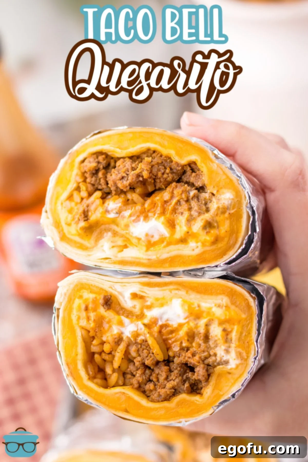 Close-up shot of a hand holding a cut Taco Bell Quesarito wrapped in foil, revealing the inside layers.