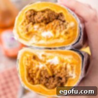 Close up of a hand holding a cut Taco Bell Quesarito, showcasing the layers of flavor.