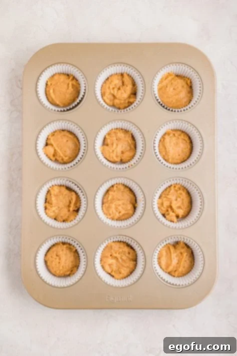 Peanut Butter & Jelly Swirl Muffins 13 A muffin tin with lined wells with peanut butter muffin batter.