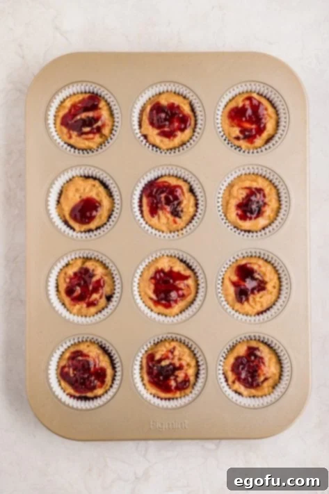 Peanut Butter & Jelly Swirl Muffins 14 Layered Peanut Butter and Jelly Muffins in a tin to bake.