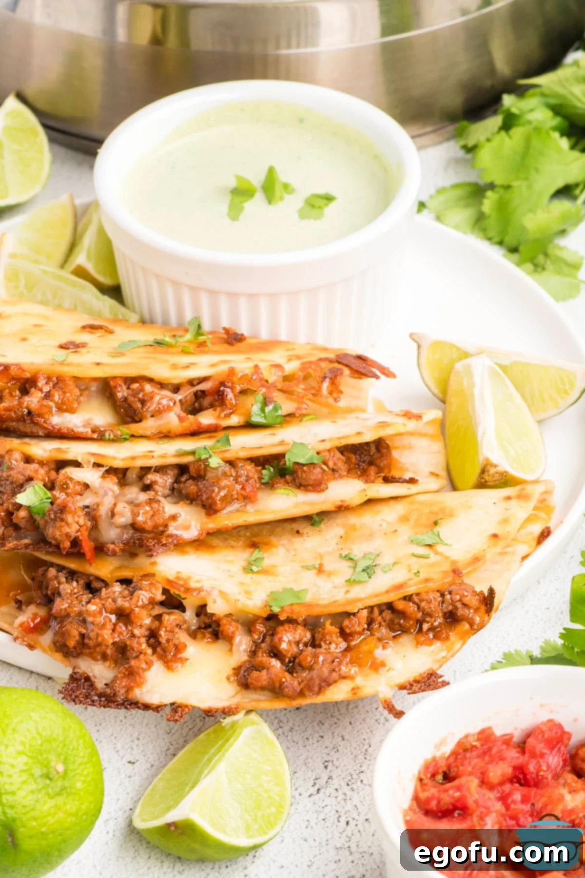 Crispy Beef Tacos stacked with a bowl of crema