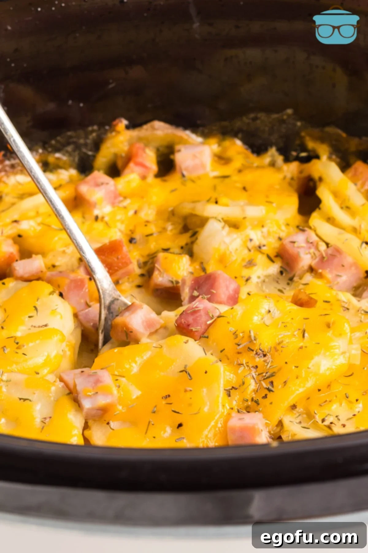 Slow Cooker Ham and Potatoes 9 A serving utensil stirring the finished Crock Pot Ham and Potatoes dish, highlighting the creamy texture and delicious ingredients.